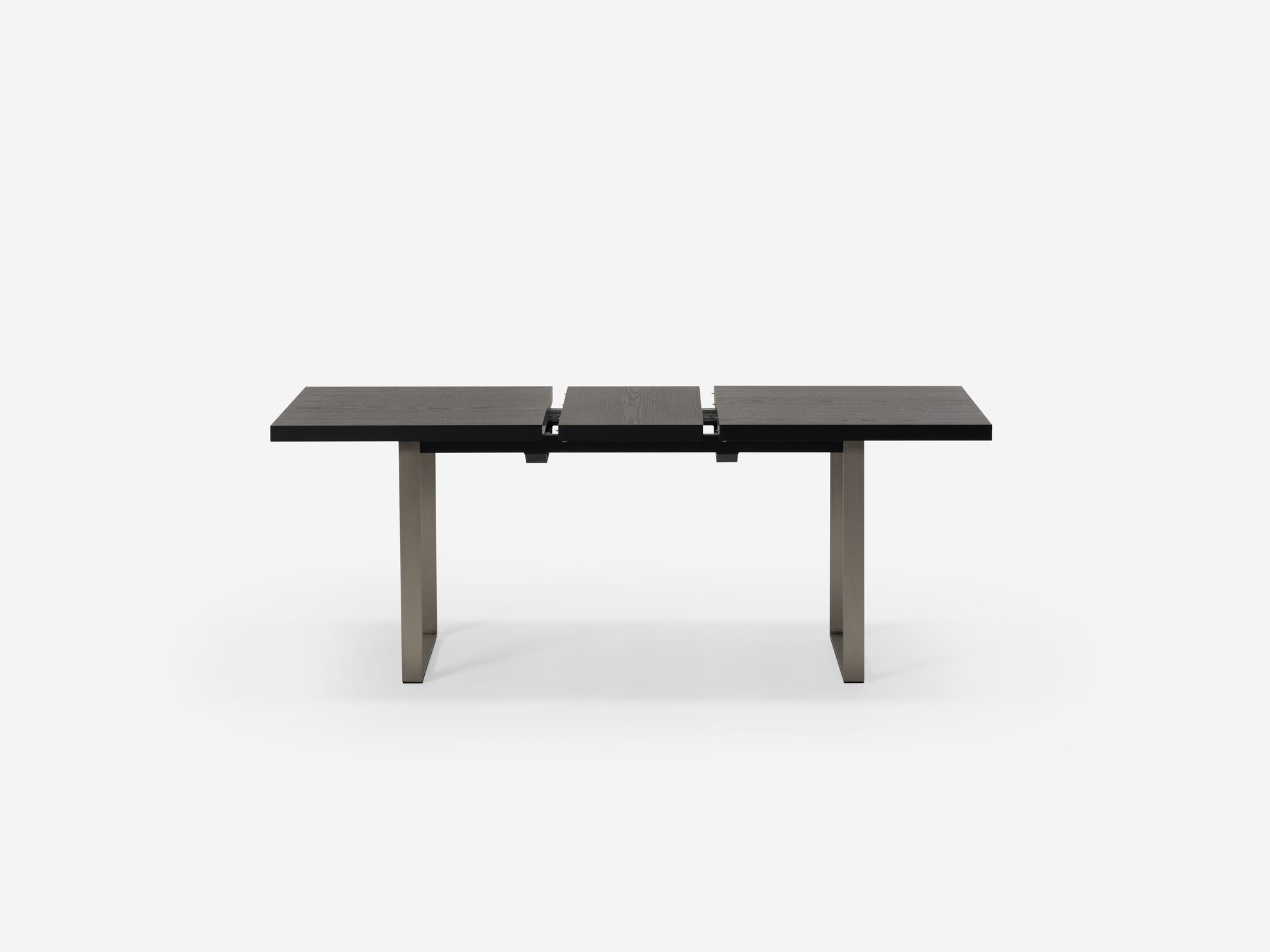 Side view of expandable dining table with stainless steel legs and black top with one leaf separated