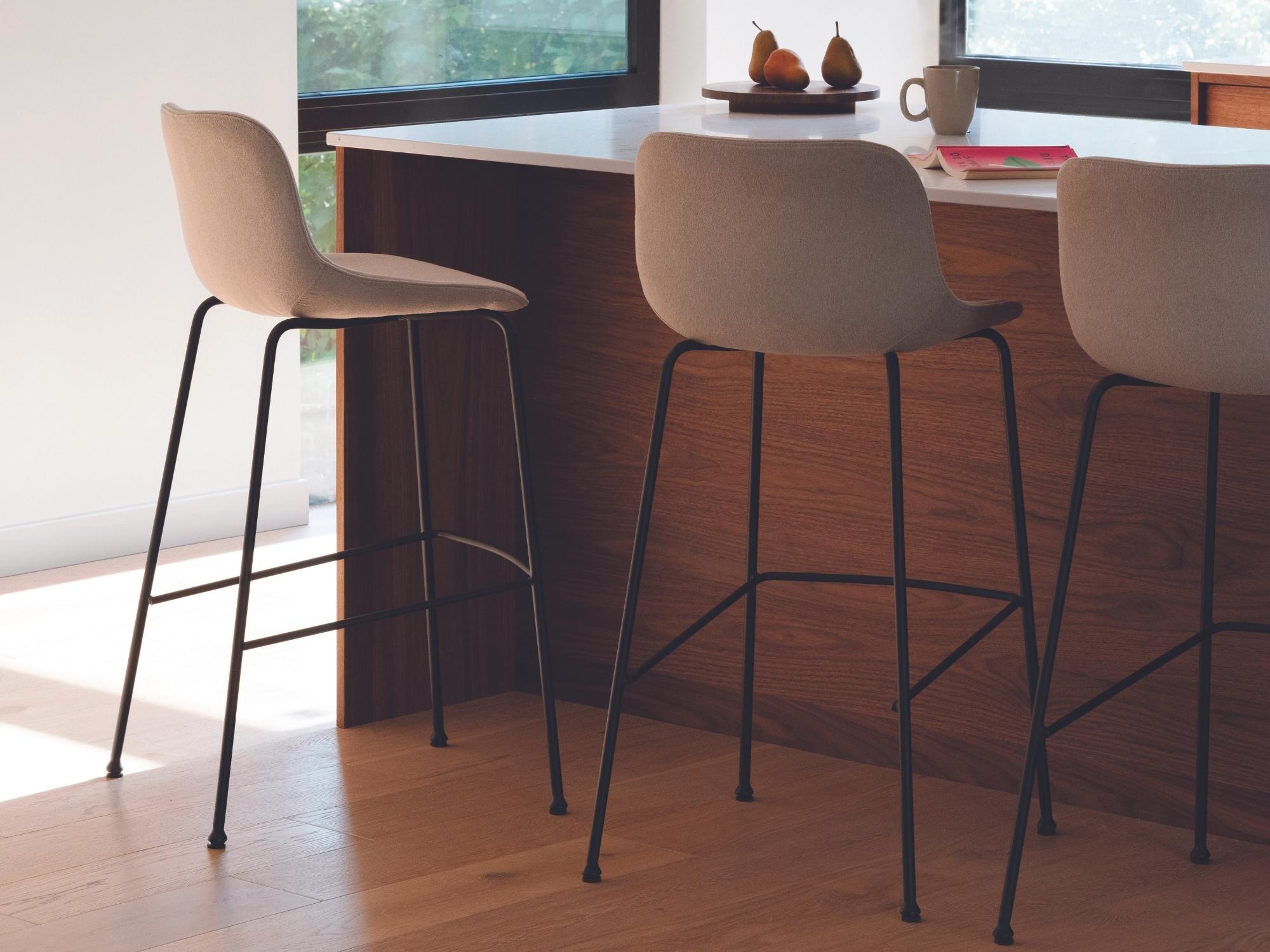 Three Oles modern counter height stools with beige seats on a hardwood floor in front of a kitchen island