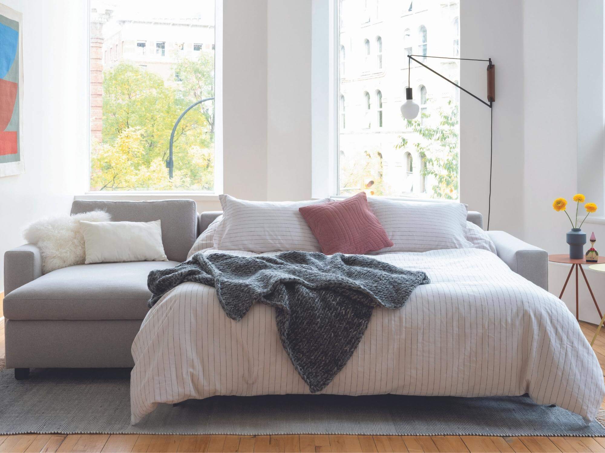 Gray knit blanket on grey sofa bed in small apartment