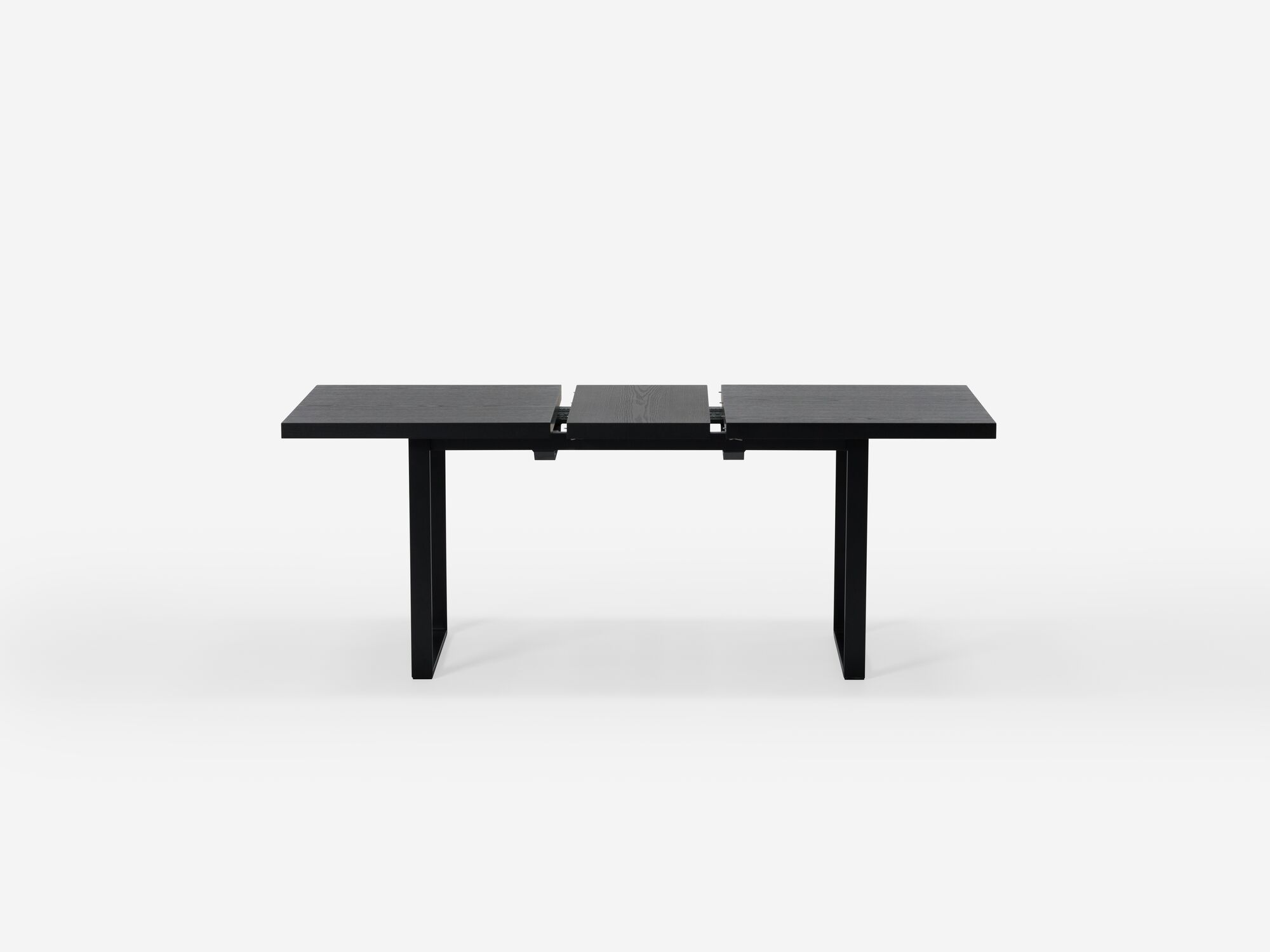 Expandable dining table with black legs and black top with one leaf separated side view