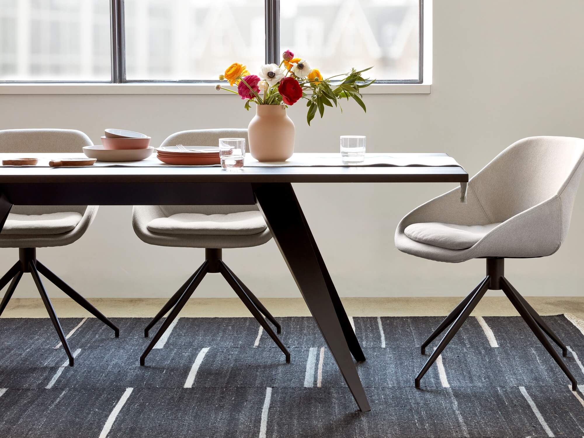 Edge of modern dining table with white upholstered dining chairs in dining room