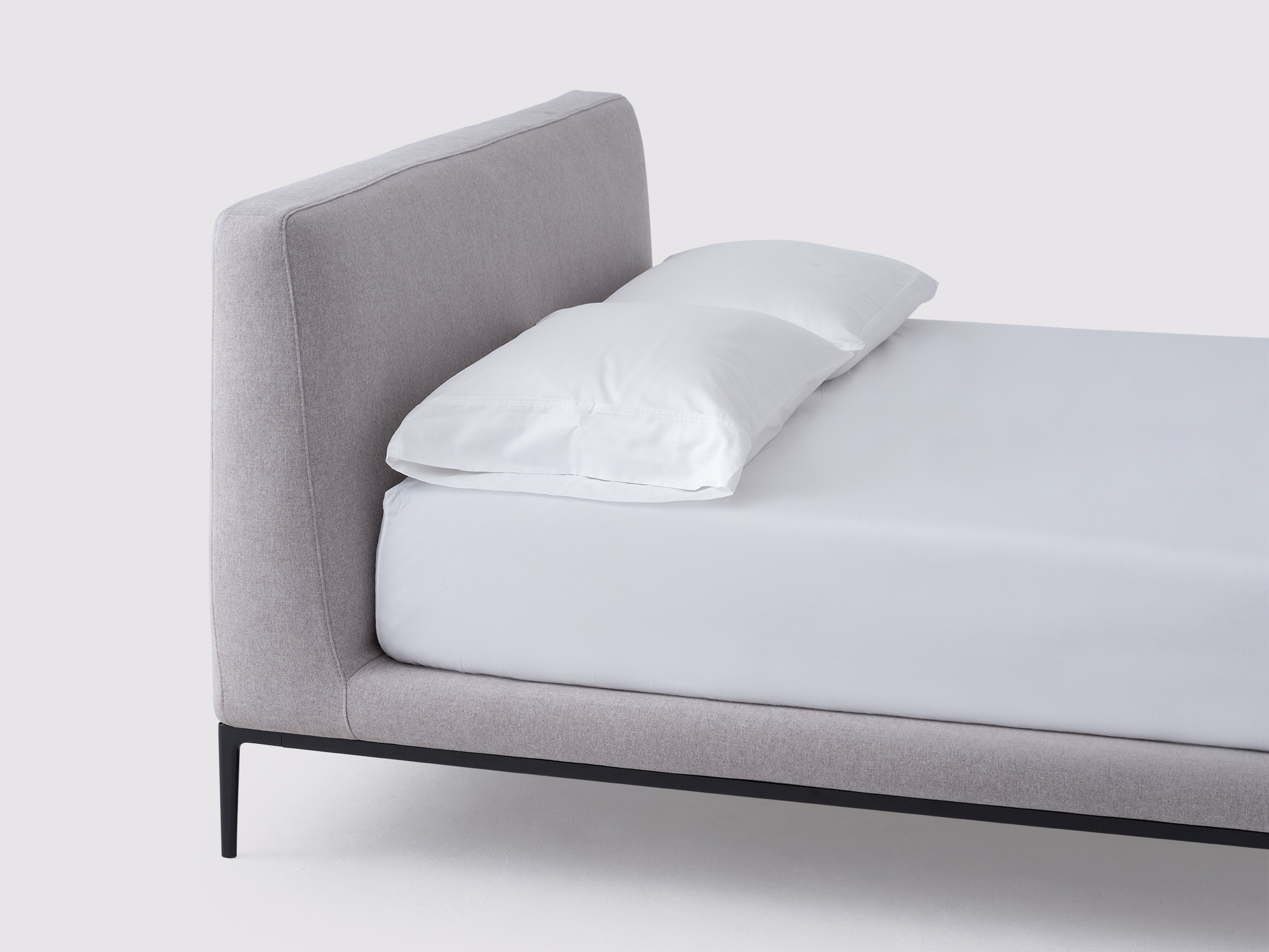 Angled detail view of the Oma upholstered bed in gray fabric