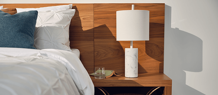 White marble table lamp on walnut bedside table