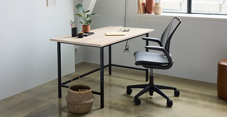 Ash top desk and grey office chair are displayed in a home office setting. Link to Humanscale seating category