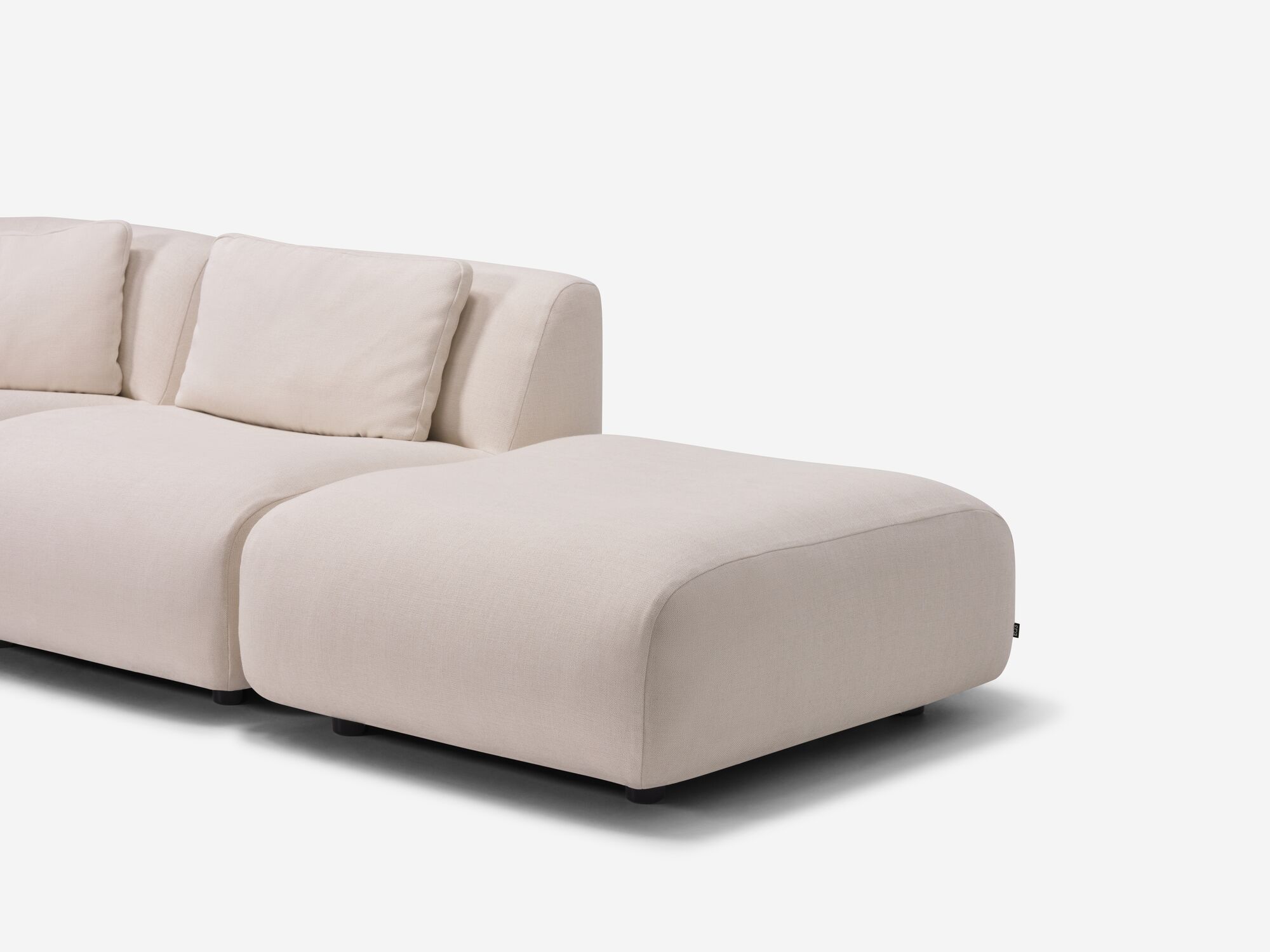 Rounded beige ottoman at end of sectional