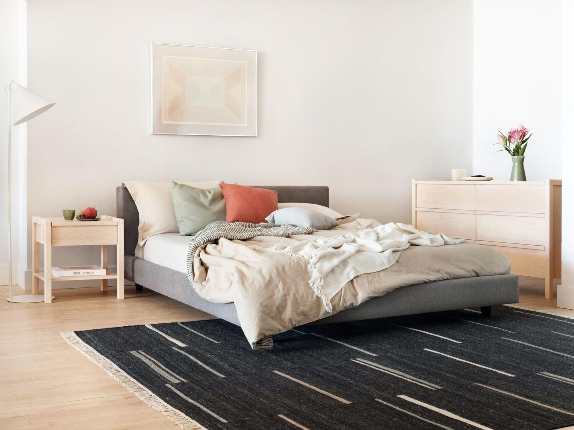 Striped black area rug under upholstered bed in modern bedroom