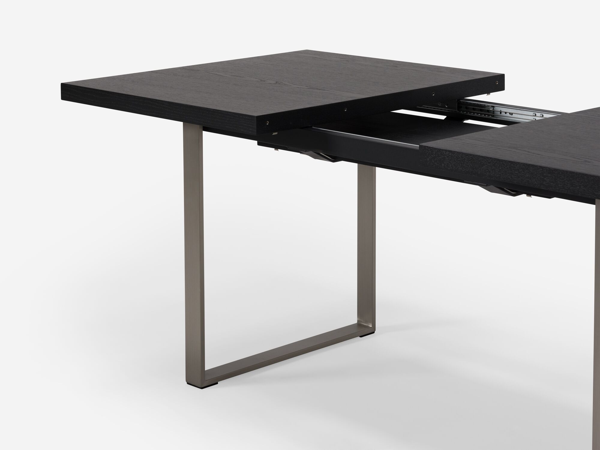 Detail view of expandable dining table with stainless steel legs and black top