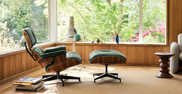 walnut and black leather eames lounge chair and ottoman are displayed in front of a large window