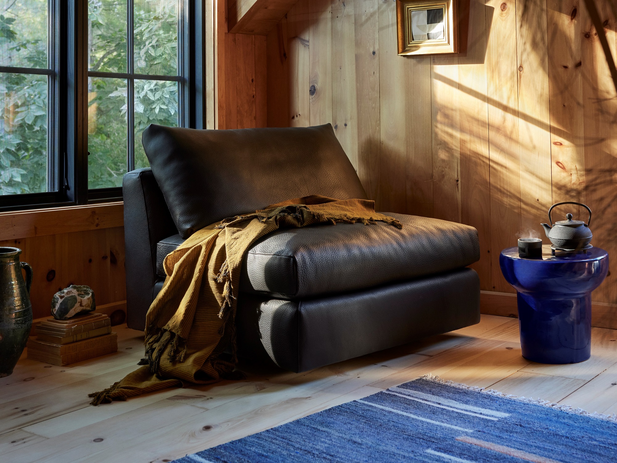 Black leather armless chair with throw blanket in wood paneled loft